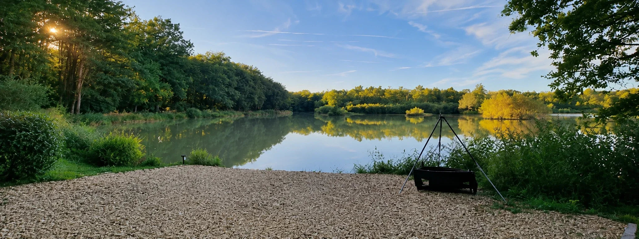 Étang du Vivier en Sologne au lever du soleil, poste de pêche gravillonné au bord de l'eau