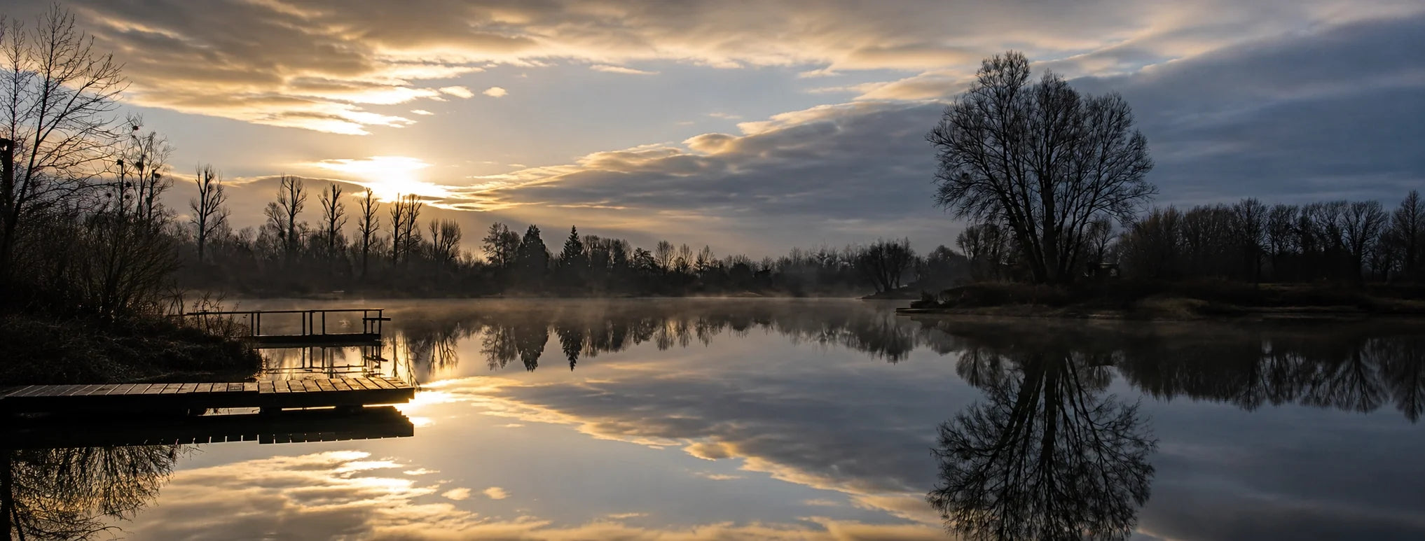 Étang de pêche à la carpe au lever du soleil, arbres reflétés sur l'eau calme