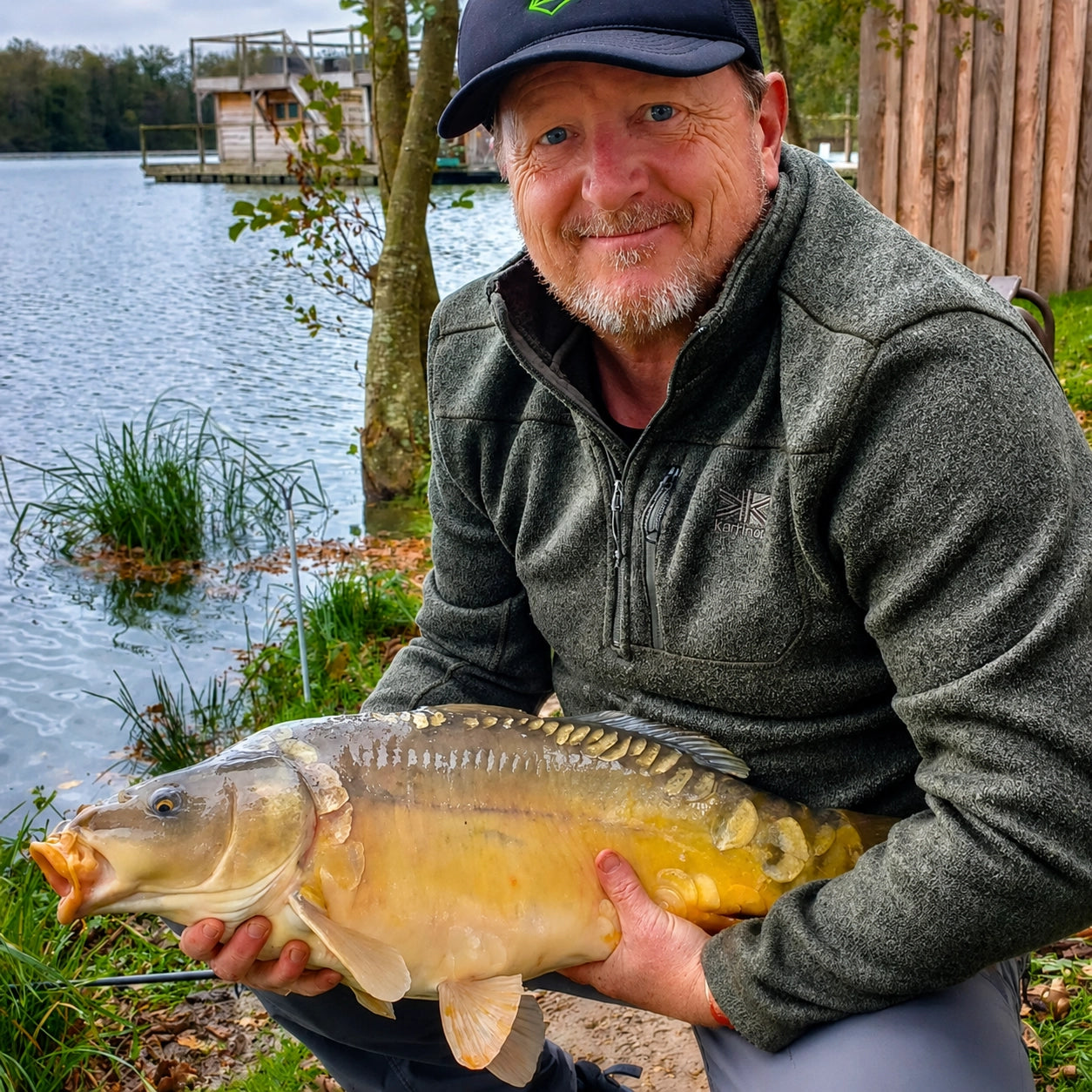 Pêcheur avec une carpe miroir prise sur l'étang du Domaine de la Dombes en fin de saison
