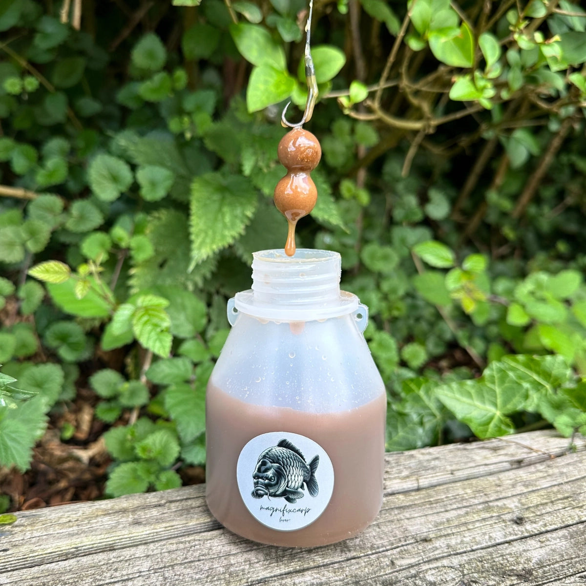 Bidon de booster liquide Liver+ suspendu au bord de l'eau, appât à carpe au signal carné