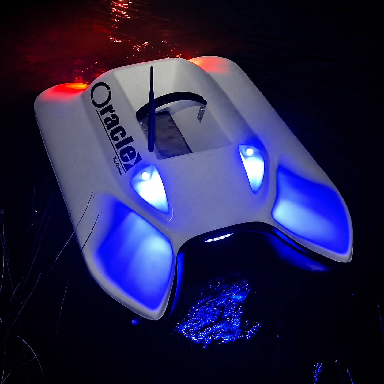 Bateau amorceur naviguant de nuit avec feux LED bleus et rouges allumés