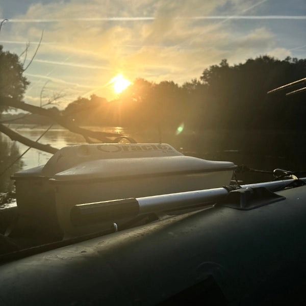 Bateau amorceur de pêche à la carpe au coucher de soleil sur un parcours de nuit