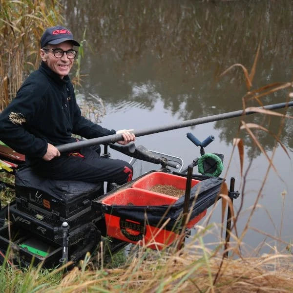 Pêcheur en carpodrome avec grande canne à emmanchement carbone et station de pêche équipée
