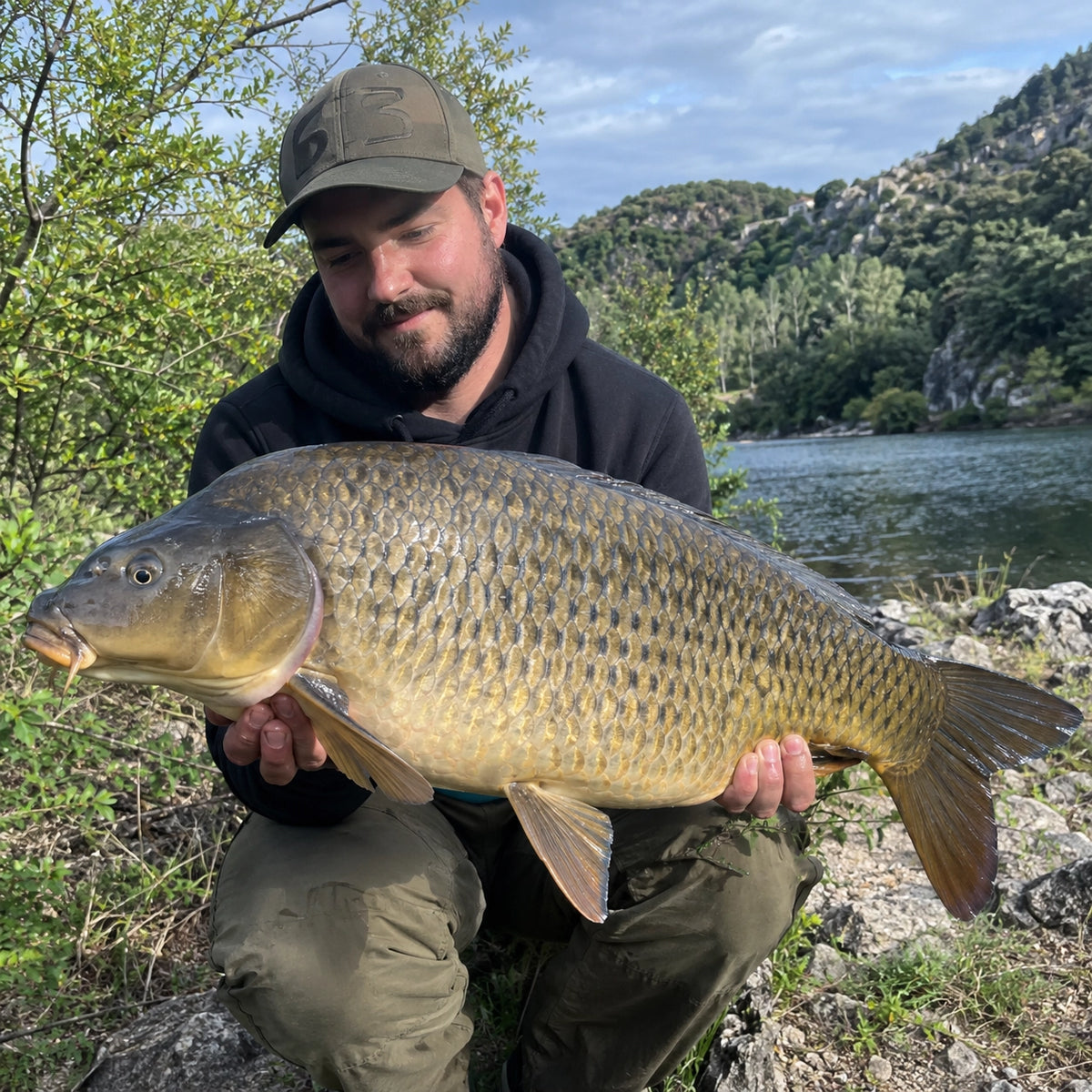 Carpiste au bord de l'eau avec une superbe carpe commune prise en Ardèche