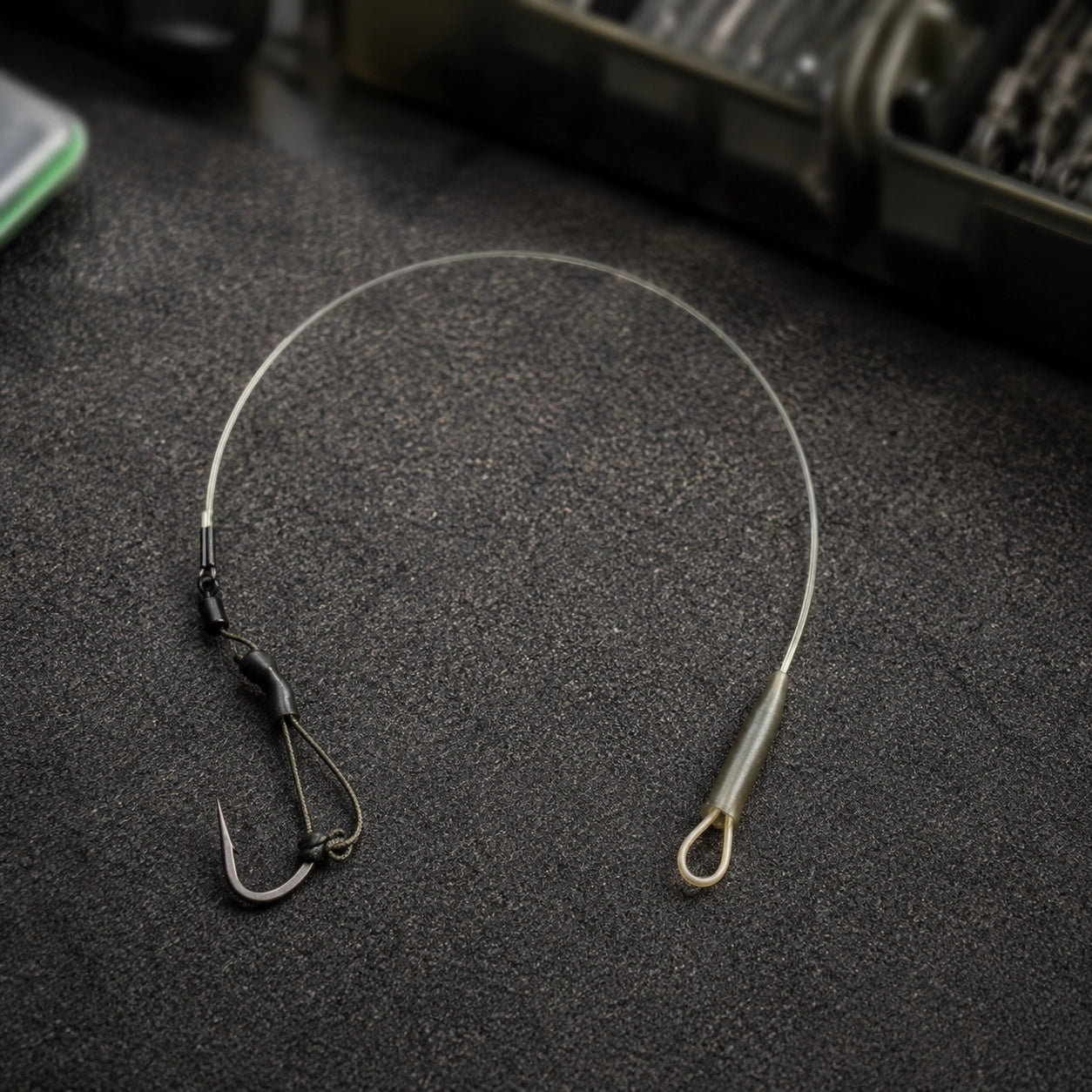 Bas de ligne carpe en fluorocarbone monté avec boucle et hameçon posé sur un tapis
