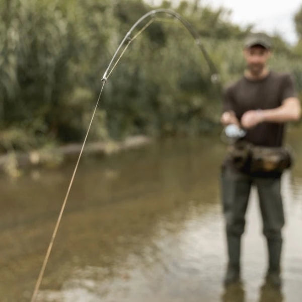 Pêcheur en action avec canne à carpe pliée en combat au bord d'une rivière, entretien après session