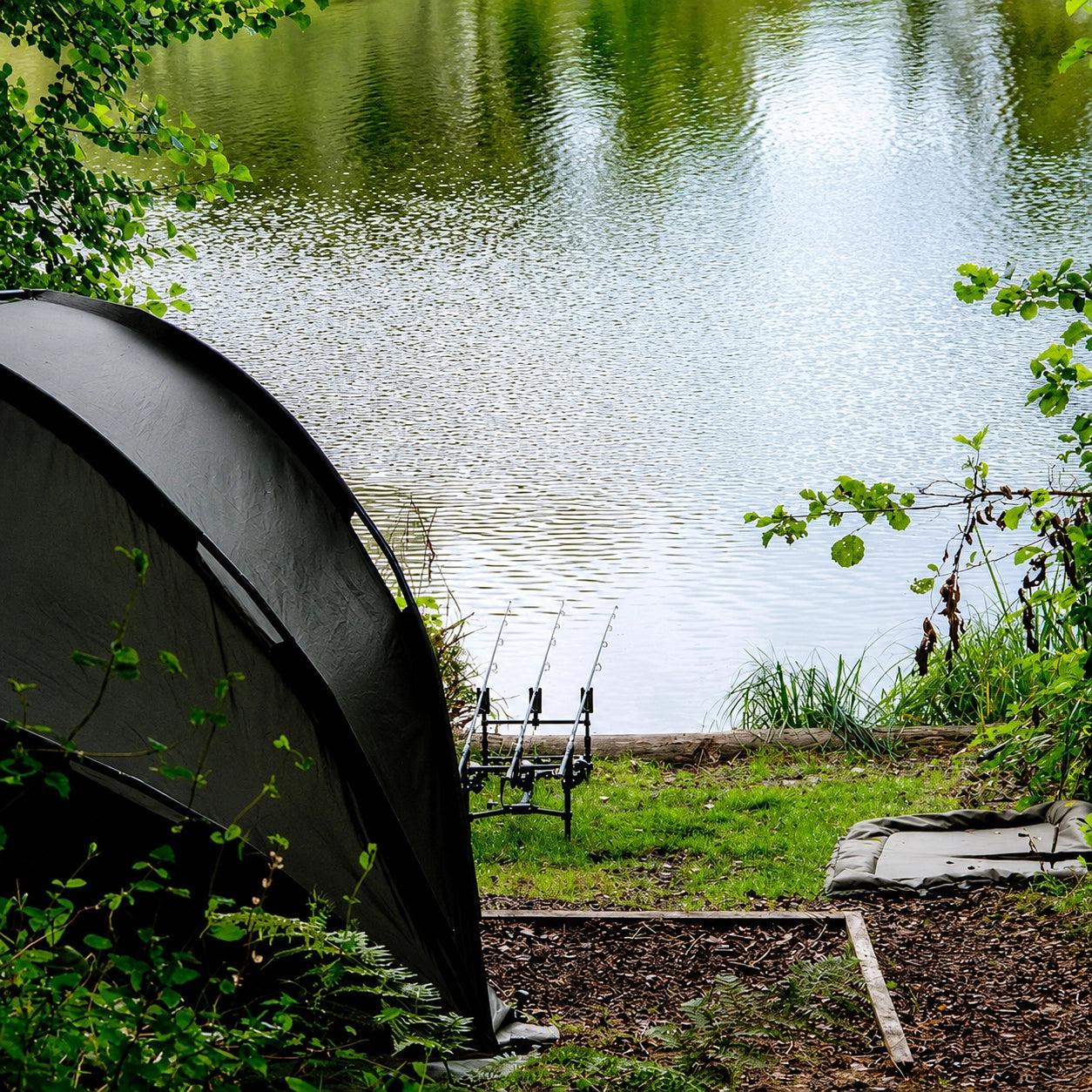 Bivouac de carpiste installé en bordure de gravière avec rod-pod et tapis de réception, configuration type pour la pêche en eau filtrée