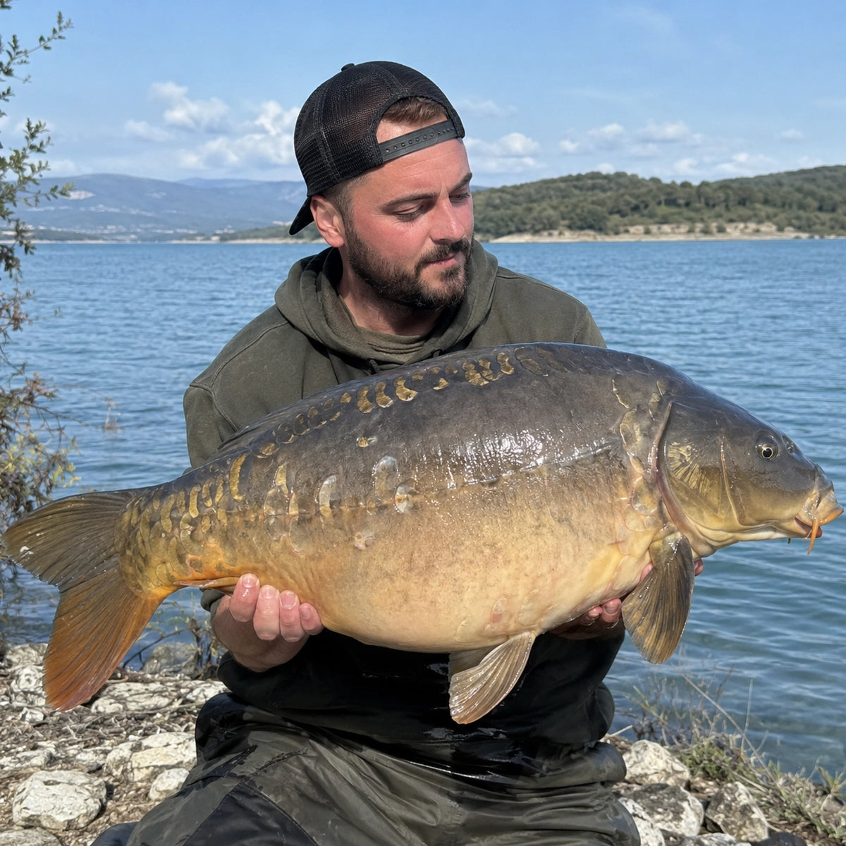 Carpiste avec une grosse carpe miroir au bord d'un grand lac audois