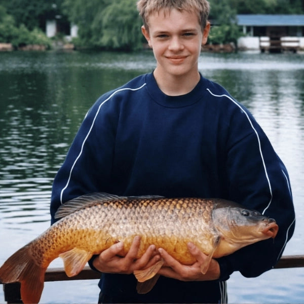 Guillaume Desesquelles à 14 ans tenant fièrement sa première carpe commune de 7,5 kg au bord d'un étang
