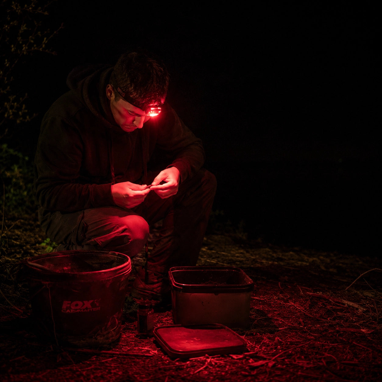 Préparation d'un montage sous la LED rouge d'une lampe frontale au bord de l'eau