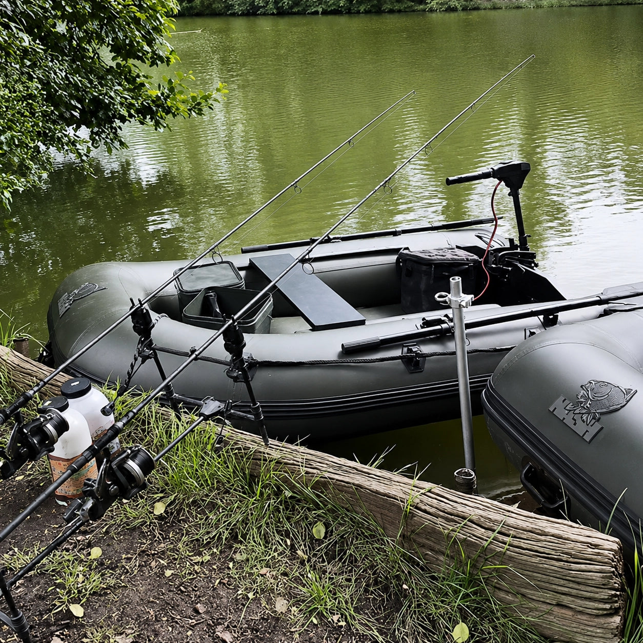 Bateau de pêche à la carpe avec moteur électrique et cannes posées au bord d'un étang