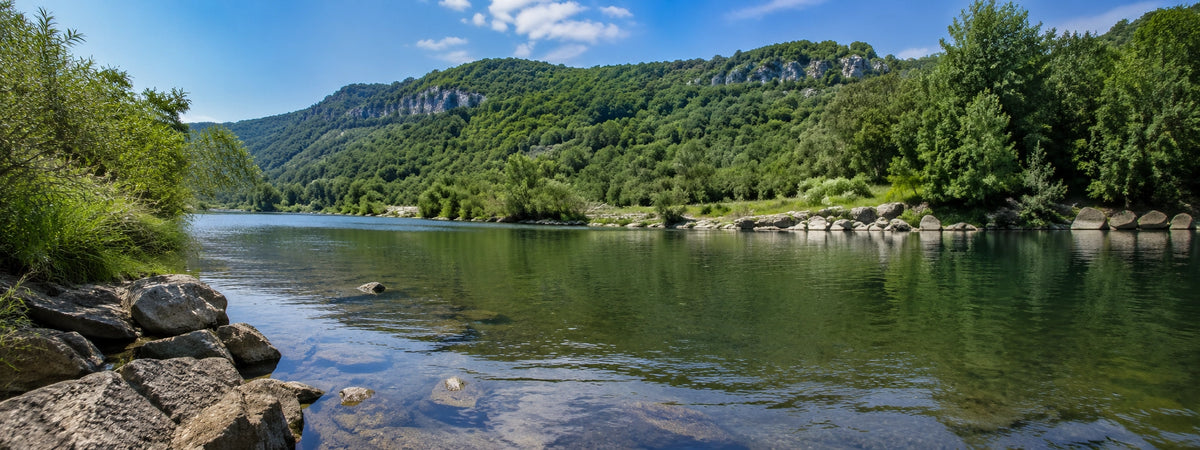 Rivière aux eaux claires bordée de falaises calcaires et de galets dans le sud de l'Ardèche