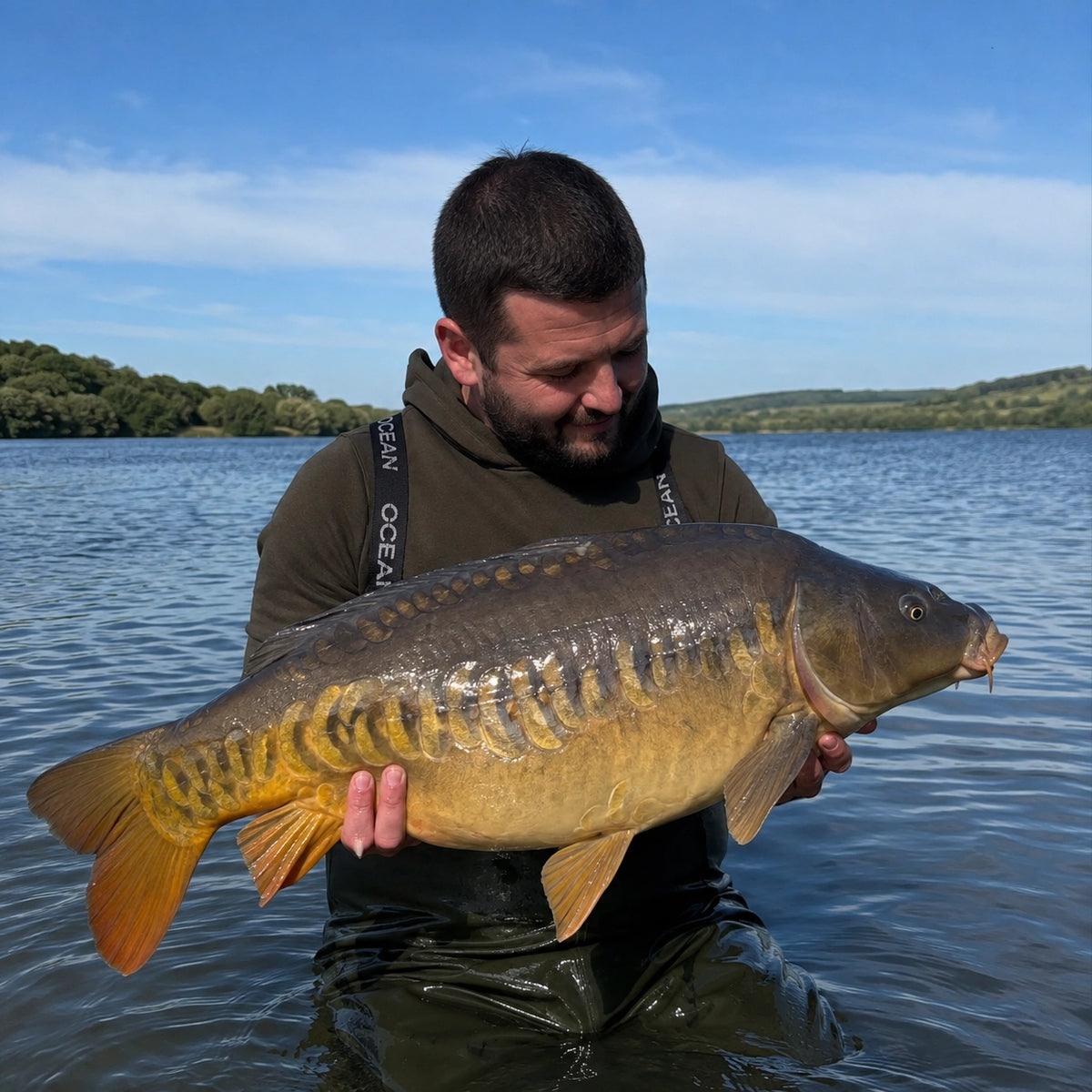 Carpiste présentant une carpe commune au bord du lac de Castelnau-Lassouts-Lous en Aveyron