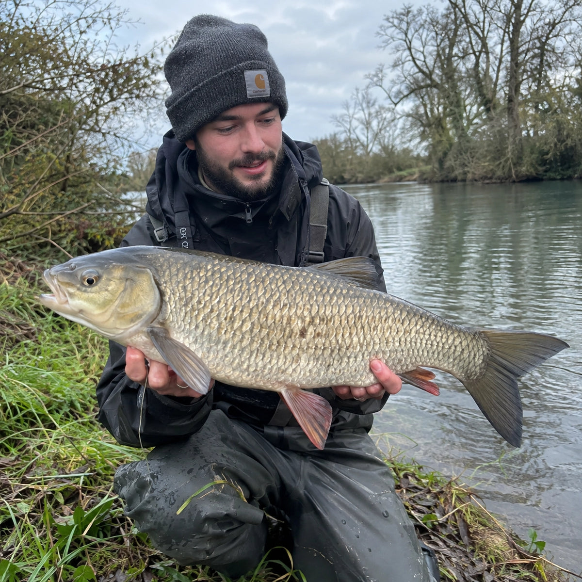 Pêcheur tenant un gros chevesne capturé en bordure de l'Orne dans le Calvados