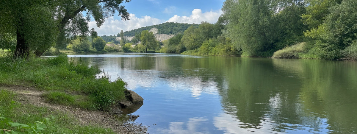 Méandre de la rivière Eure bordé d'arbres, avec une falaise crayeuse en arrière-plan