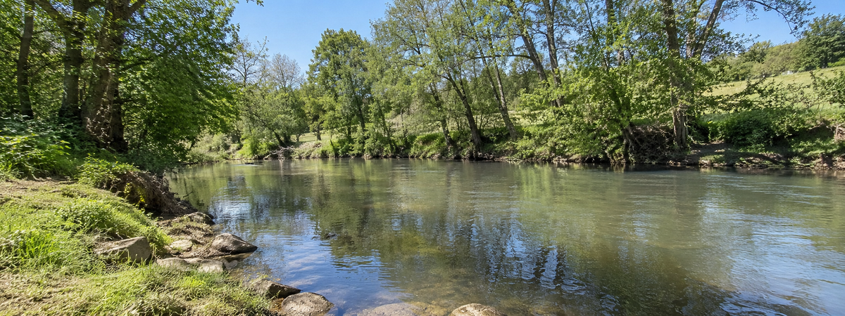 Rivière du Gers bordée d'arbres au pied des coteaux gascons
