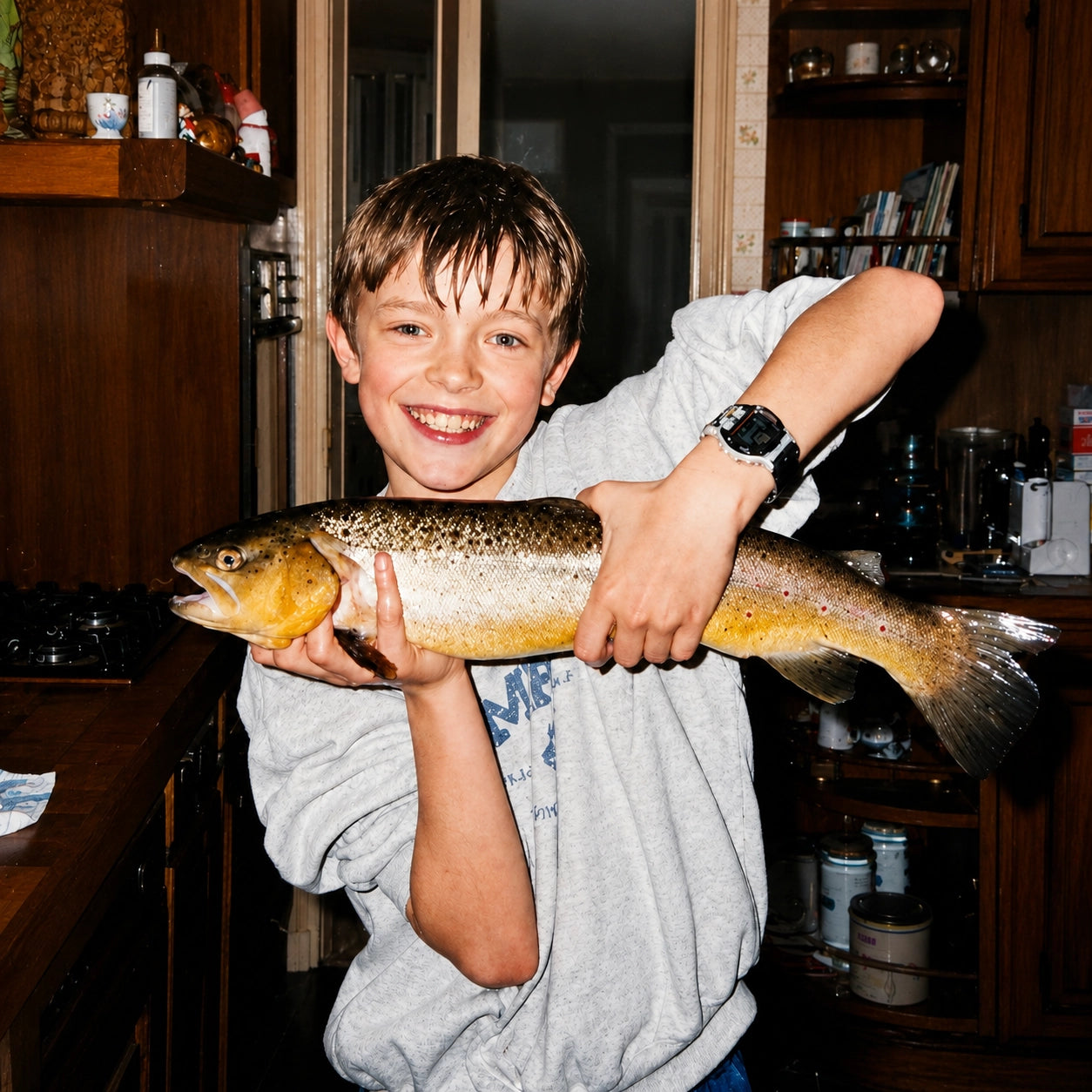 Enfant souriant tenant une grosse truite, transmission de la pêche par les anciens