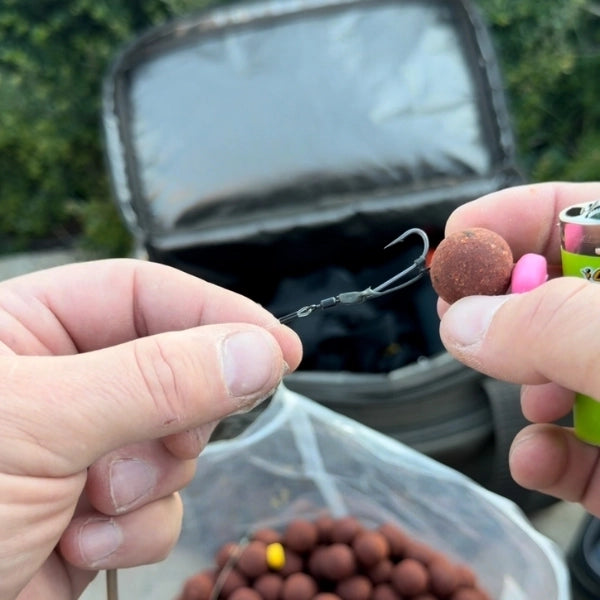 Préparation minutieuse d'une bouillette montée sur cheveu la veille d'une session de pêche à la carpe