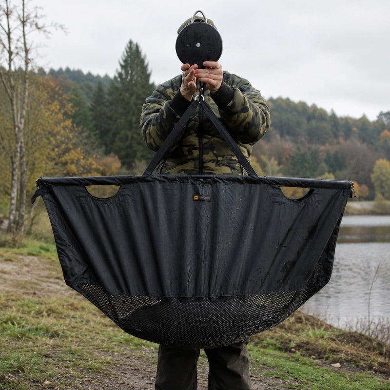 Pêcheur tenant un sac de pesée carpe accroché à un peson