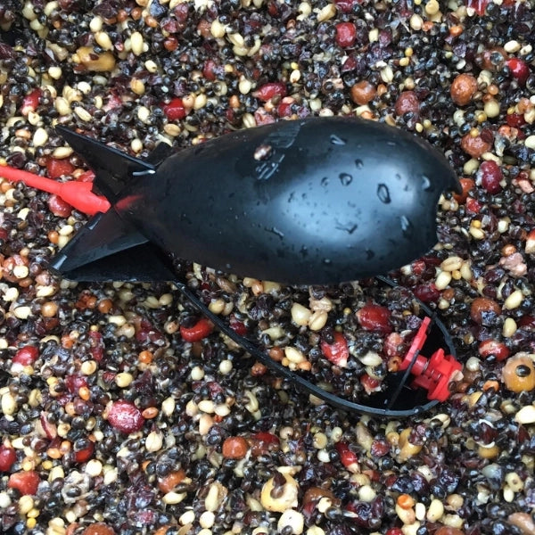 Spomb noir prêt à lancer sur un mélange de graines et de bouillettes, base d'un amorçage efficace